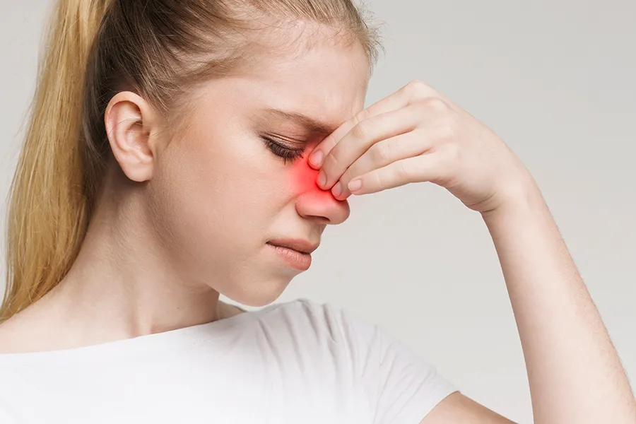 Allergic-Rhinitis-Clinic A woman grimaces and rubs the bridge of her nose due to sinus irritation. Get treatment for allergic rhinitis from Nonkulie Dladla, M.D. in Manhattan.