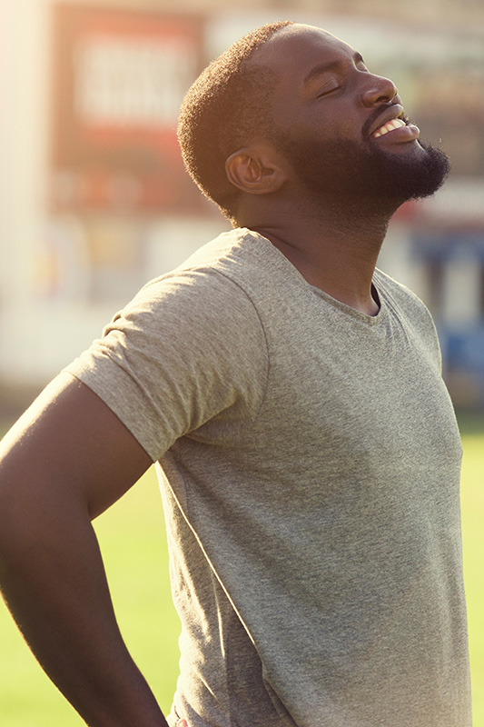 Allergic-Rhinitis-Treatment A black man in a t-shirt smiles and raises his face to the sun due to relief from allergies. Get treatment for allergic rhinitis from Nonkulie Dladla, M.D. in Manhattan.