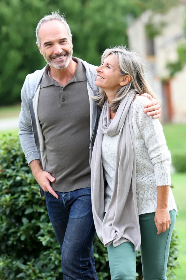 Bioidentical-Hormone-Therapy-Treatment A mature couple in gray toned clothes and jeans walk happily outside, happy with their successful bioidentical hormone treatments from Nonkulie Dladla, M.D. in Manhattan.
