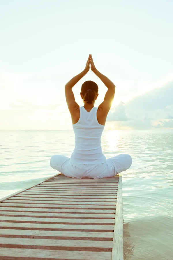Bioregulatory-Care-Treatment A woman does yoga on a pier. Get Bioregulatory Care from Nonkulie Dladla, M.D. in Manhattan.