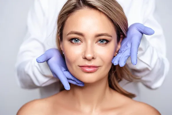 Botox-Doctor Close up of a woman's face with a doctor wearing rubber gloves standing behind her holding his hands around her face to show the amazing Botox Cosmetic treatment from Nonkulie Dladla, M.D. in Manhattan.