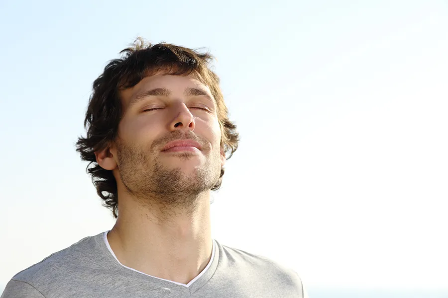 Breathwork-Clinic A man with closed eyes breathes in the fresh air. Get breathwork treatment from Nonkulie Dladla, M.D. in Manhattan.