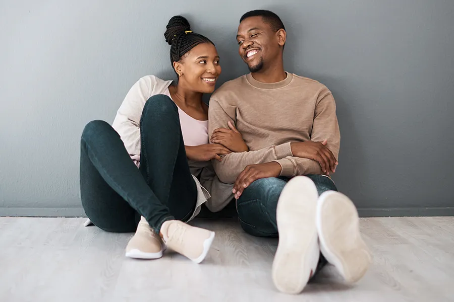 Exosome-Therapy-Clinic A healthy black couple sits against a gray wall smiling. Schedule exosome therapy from Nonkulie Dladla, M.D. in Manhattan.