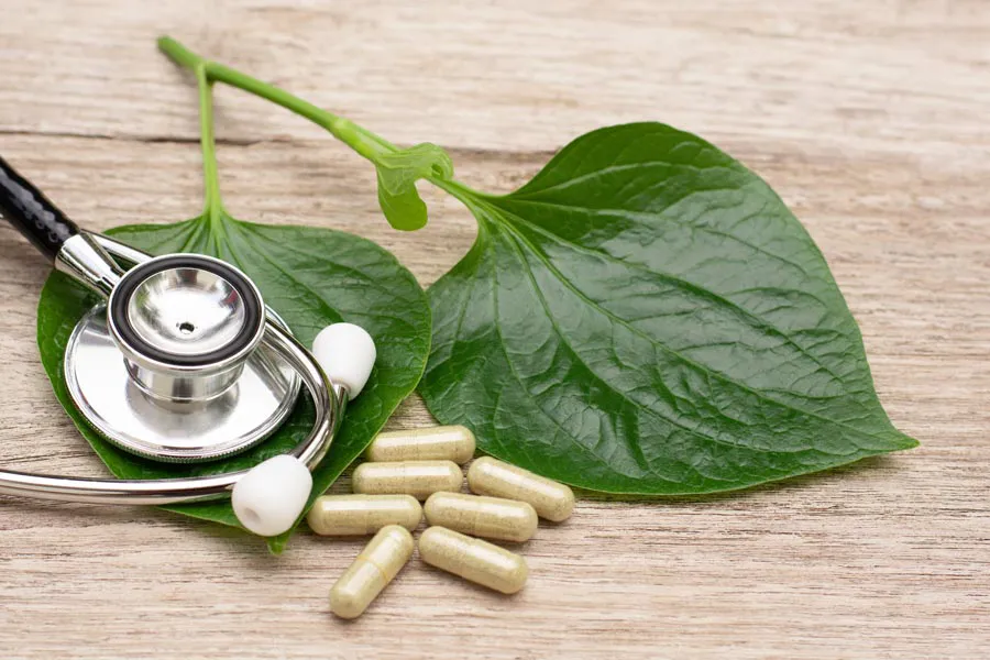Integrative-Medicine-Clinic A stethoscope, leaves, and medicine capsules on a wood table, representing Integrative Medicine provided by Nonkulie Dladla, M.D. in Manhattan.