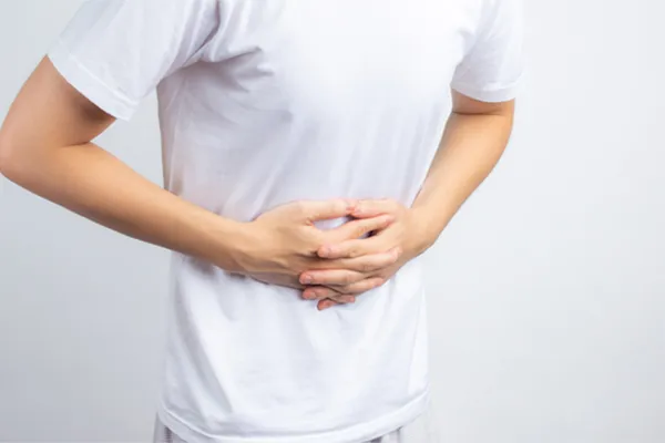 Irritable-Bowel-Syndrome-Clinic A person holding their stomach in visible discomfort against a plain background. Nonkulie Dladla, M.D. treats irritable bowel syndrome with functional medicine in Manhattan.