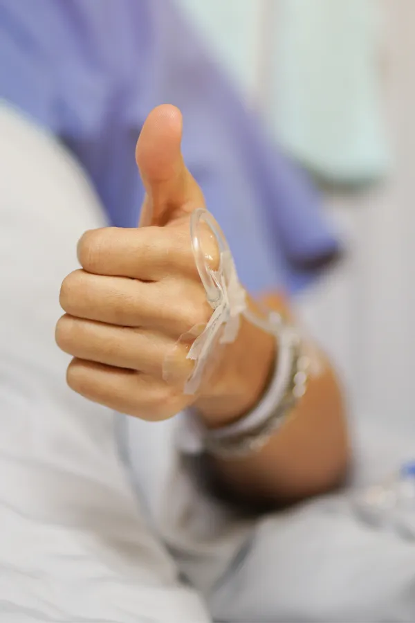 MEDJET-Provider-Treatment A patient with an IV in a hospital bed gives the thumbs up. Get premiere MEDJET services from Nonkulie Dladla, M.D. in Manhattan.