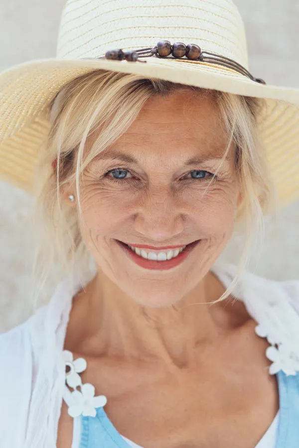 Menopause-Treatment A beautiful, smiling older woman with blonde hair and a sunhat, happy with menopause treatment from Nonkulie Dladla, M.D. in Manhattan.