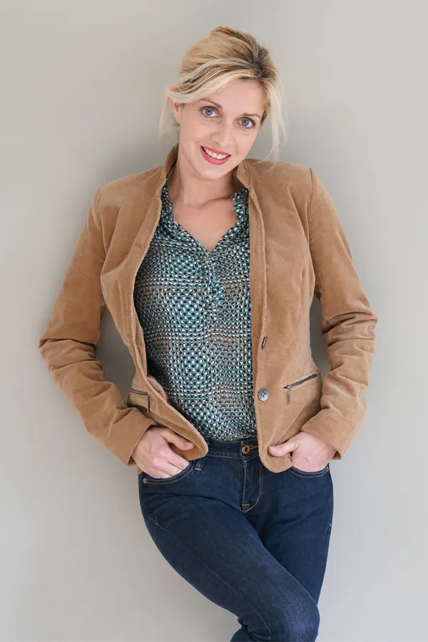 Metabolic-Syndrome-Treatment A smiling blonde woman in a tan leather jacket leans against a gray wall. Schedule metabolic syndrome from Nonkulie Dladla, M.D. in Manhattan.