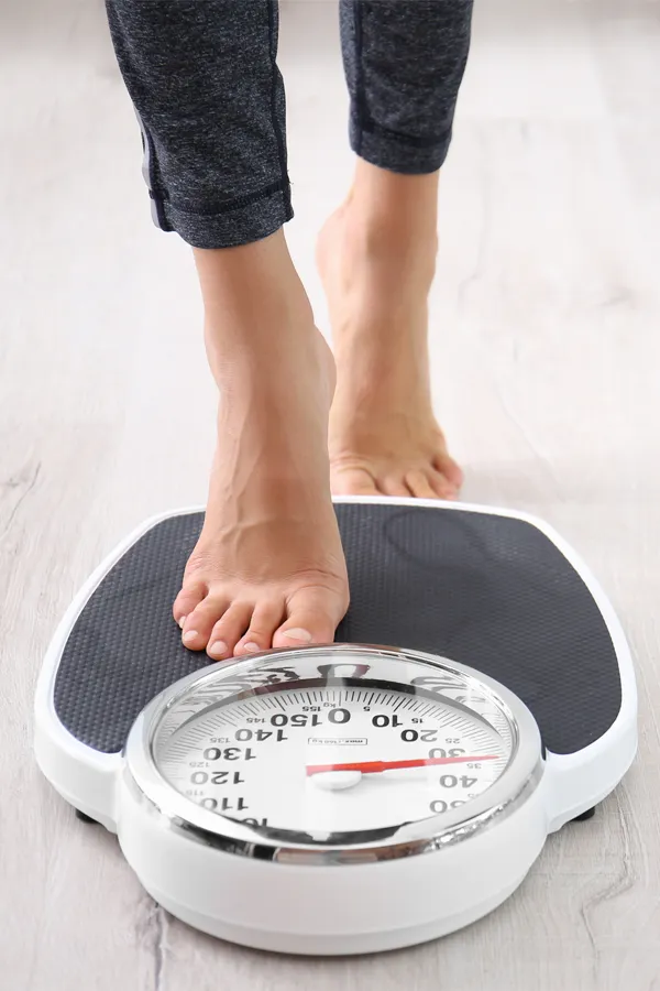 Obesity-Treatment Close up of feet stepping onto a scale. Receive expert functional medicine for obesity treatment by Nonkulie Dladla, M.D. in Manhattan.