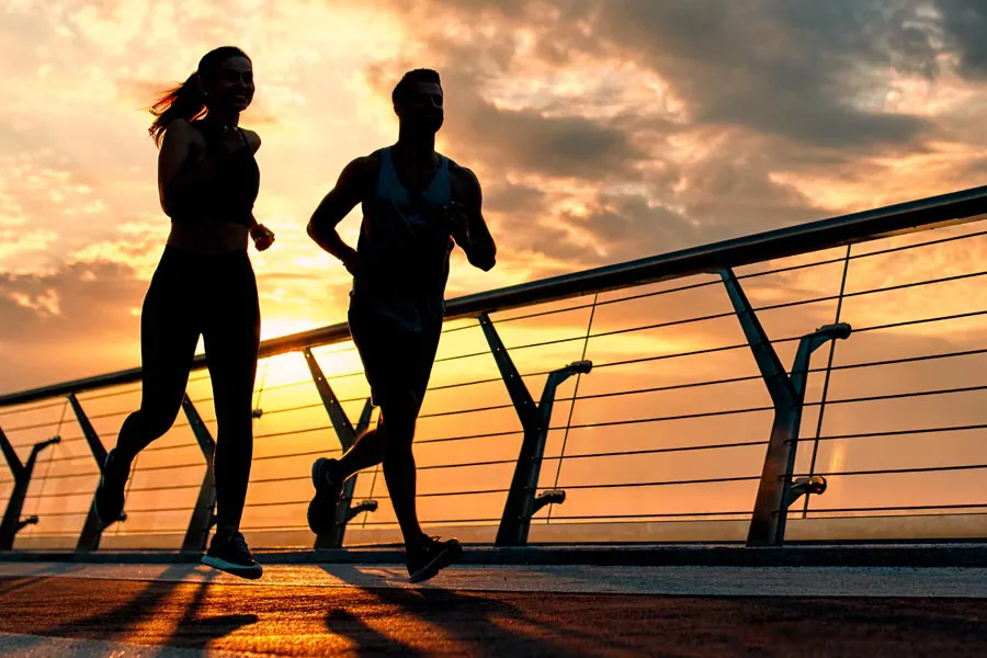 Performance-Enhancing-Peptides-Doctor A couple jogging on a bridge at sunrise, representing performance enhancing peptide therapy from Nonkulie Dladla, M.D. in Manhattan.