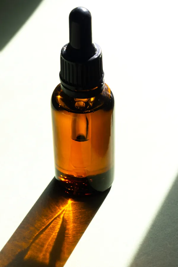 Performance-Enhancing-Peptides-Treatment A brown dropper bottle on a table lit by sunlight, representing performance enhancing peptide treatment from Nonkulie Dladla, M.D. in Manhattan.