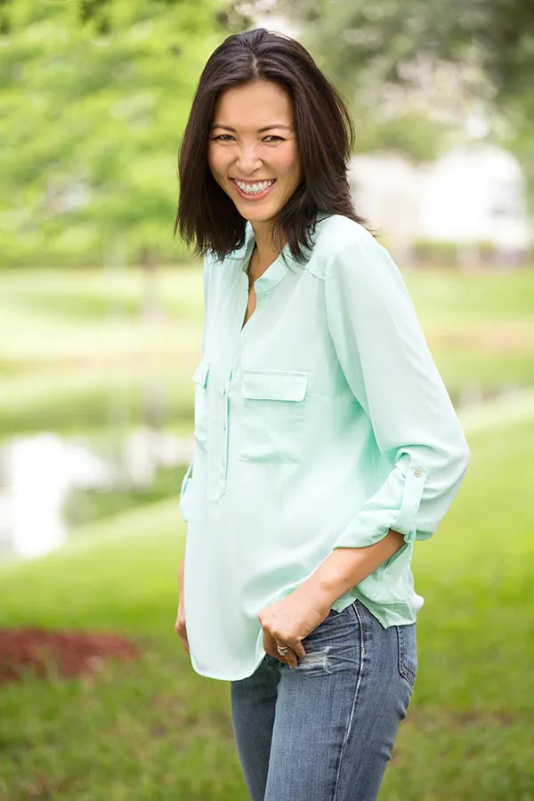 Perimenopause-Treatment A middle-aged brunette woman in a light green button-up shirt stands outside smiling, happy with her perimenopause treatment from Nonkulie Dladla, M.D. in Manhattan.