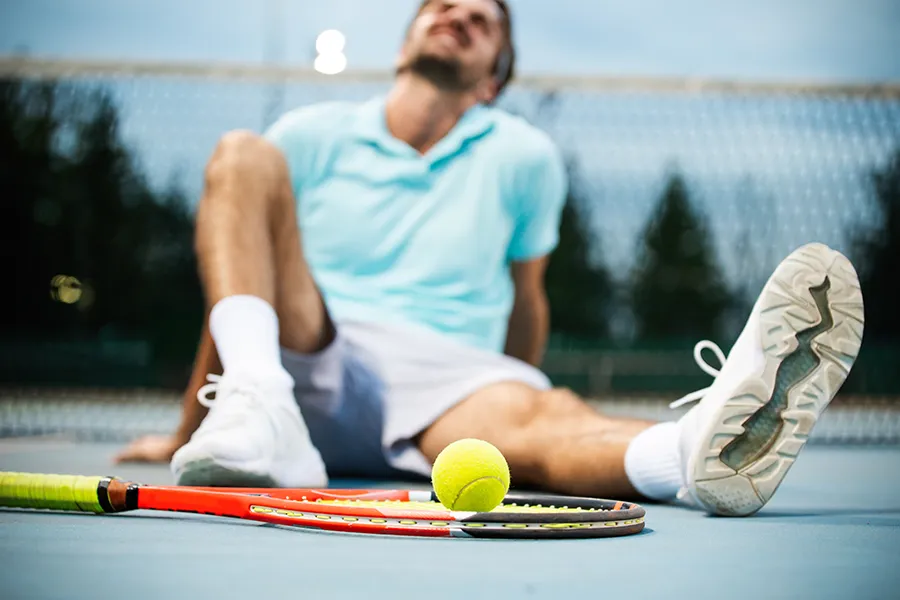 Regenerative-Medicine-for-Injury-Rehabilitation-Clinic A man sitting on a tennis court with an injury. Schedule Regenerative Medicine for Injury Rehabilitation from Nonkulie Dladla, M.D. in Manhattan.