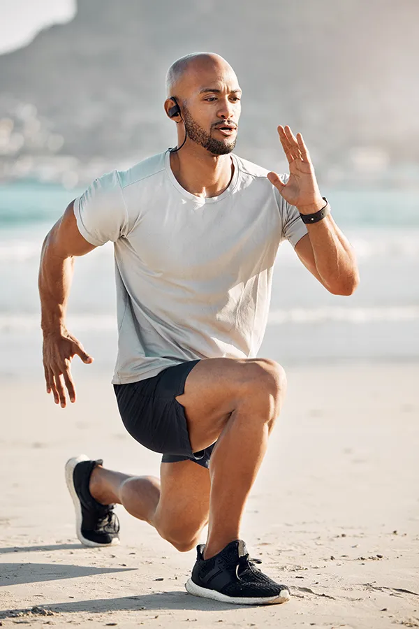 Regenerative-Medicine-for-Sore Muscles-Treatment A man does lunges on the beach. A man sitting on a tennis court with an injury. Get Regenerative Medicine for Sore Muscles from Nonkulie Dladla, M.D. in Manhattan.