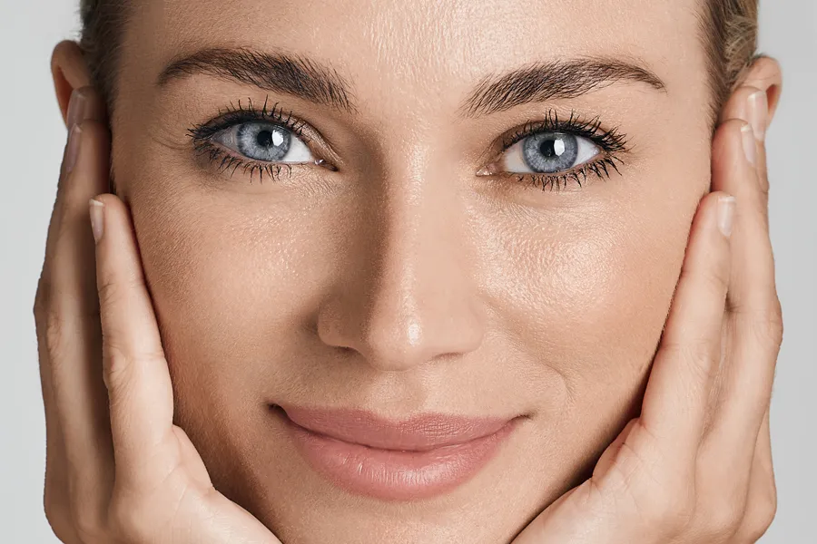 SKINVIVE-Filler-Clinic A beautiful vibrant woman touching her cheeks. Schedule SKINVIVE dermal filler treatment from Nonkulie Dladla, M.D. in Manhattan.
