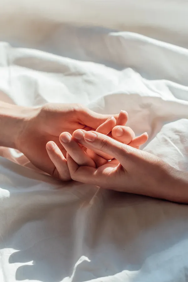 STD-Testing-Treatment Hands clasping on top of sheets. Get STD testing from Nonkulie Dladla, M.D. in Manhattan.