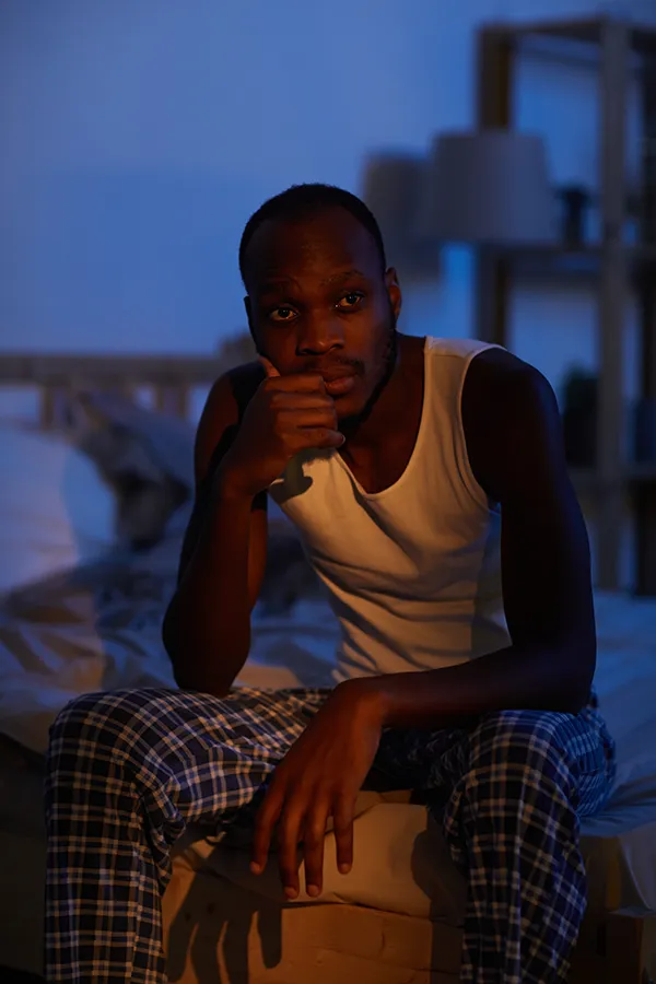 Sleep-Disorders-Treatment A man sits on the edge of his bed concerned that he can't sleep. Get treatment for sleep disorders from Nonkulie Dladla, M.D. in Manhattan.