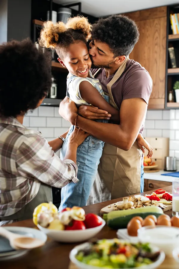 Type-2-Diabetes-Treatment Happy family of three smiling while cooking a healthy meal at home after receiving expert functional medicine for type 2 diabetes treatment by Nonkulie Dladla, M.D. in Manhattan.