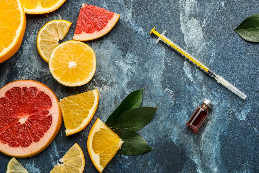 Vitamin-Injection-Doctor A gray marble countertop covered with sliced fruit and a syringe and vial, representing vitamin injections from Nonkulie Dladla, M.D. in Manhattan.