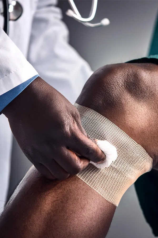 Wound-Care-Treatment A clinician treats a wound on a patient's knee. Get wound care treatment from Nonkulie Dladla, M.D. in Manhattan.
